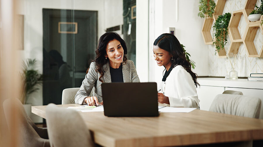 Two people sitting at a table with a laptop.