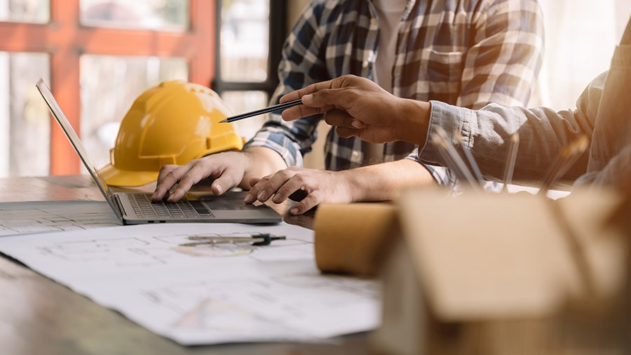 A person in a construction site working on a laptop.