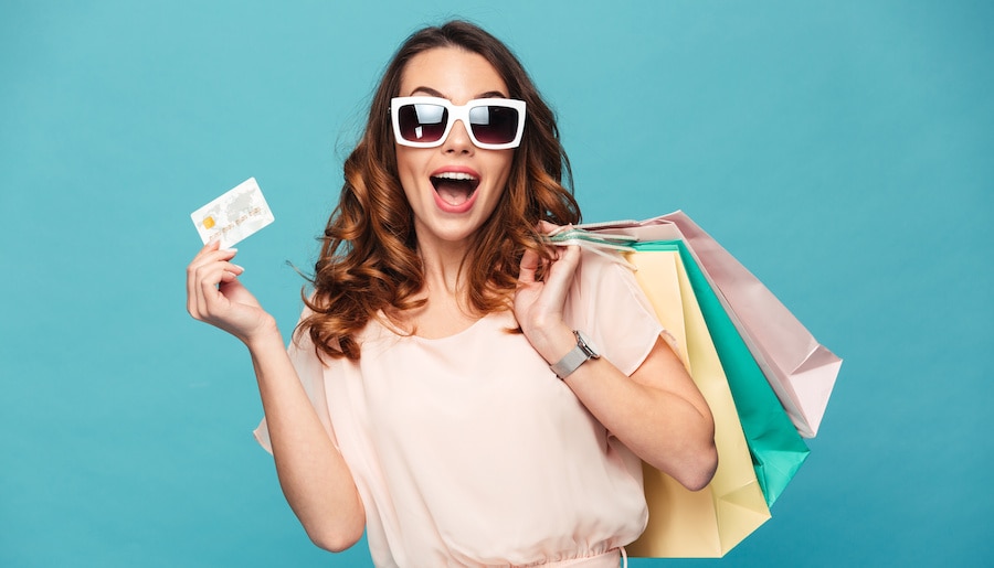 A person in a shopping cart holding a shopping bag.