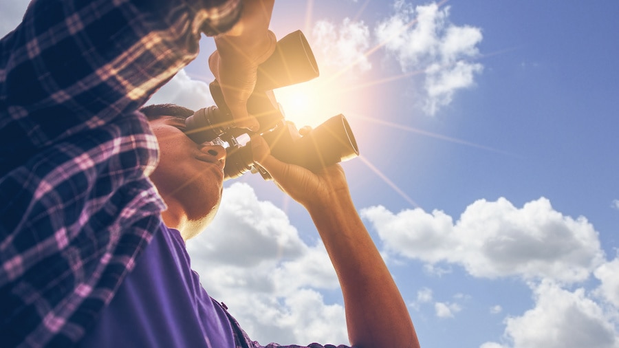 A person holding a camera up to the sky.