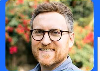 A person with a smile on his face wearing glasses.