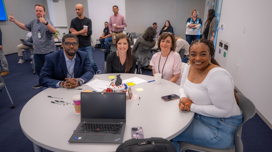 A group of people sitting at a table with laptops.