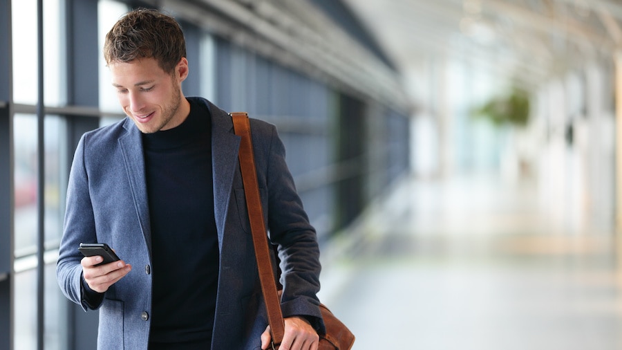 A person in a suit and tie is walking with a suitcase.