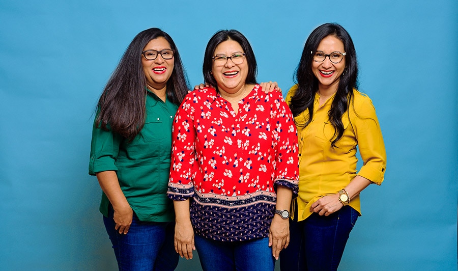 Three people standing together in front of a blue background.