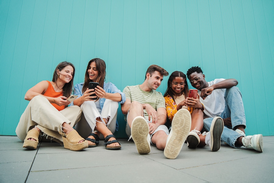 Group of young people sharing apps on their phones.