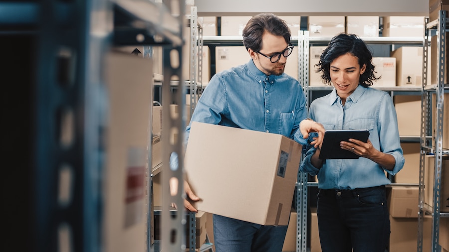 Two people looking over inventory on a device.