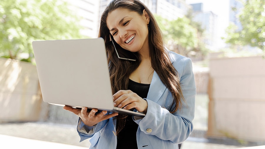 A person smiles as she holds a laptop.
