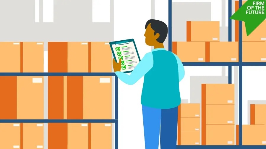 A warehouse worker in a blue vest reviews a clipboard checklist while inspecting stacks of organized inventory boxes on shelves.